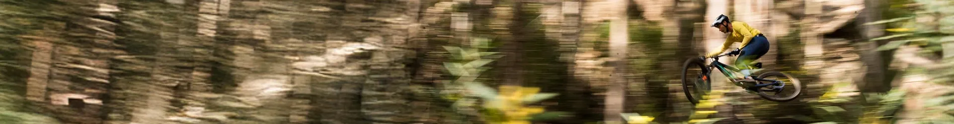 Sant Cruz MTB rider jumping pan shot in the woods