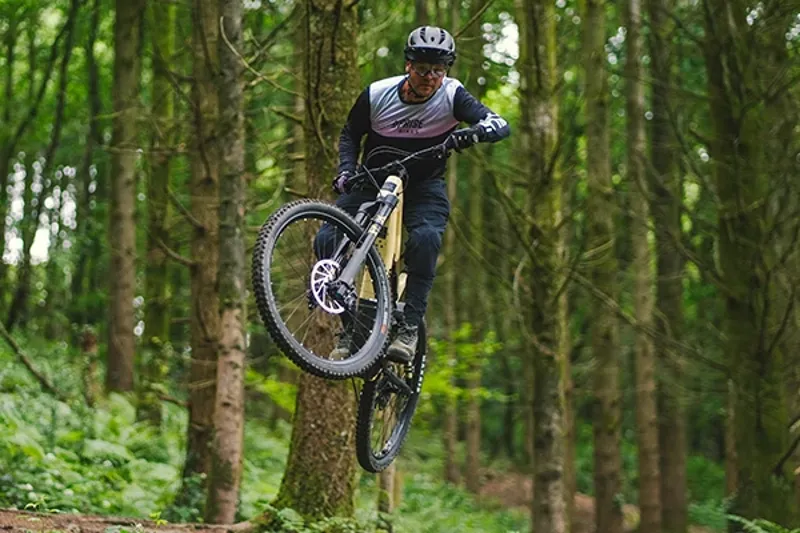 Full suspension electric mountain bike jumping on a technical trail