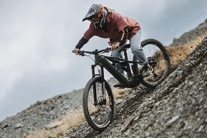 Woman riding a Merida e180 down steep loose terrain