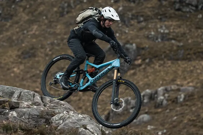 Close-up of mountain bike in a loose turn showing suspension and brake components