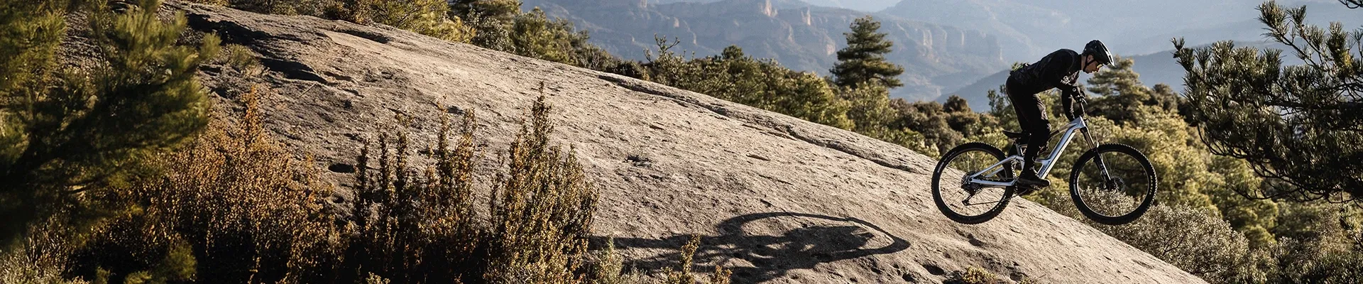 Riding the Orbea Rise electric mountain bike on a rock slab in the big mountains